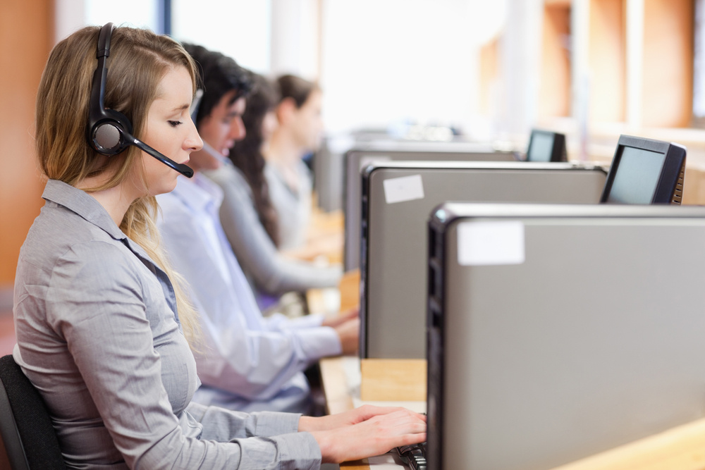 Operators using a computer in call center with the camera focus on the foreground